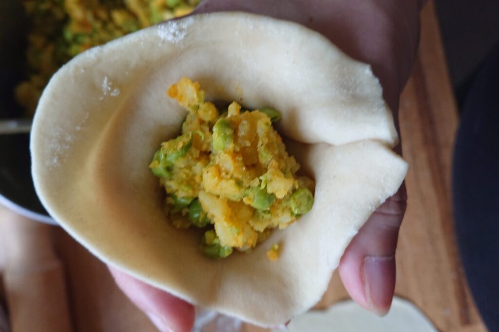 Indische Samosas bei der Entstehung: Blick von Oben auf die rohe Füllung aus Kartoffeln und Erbsen.